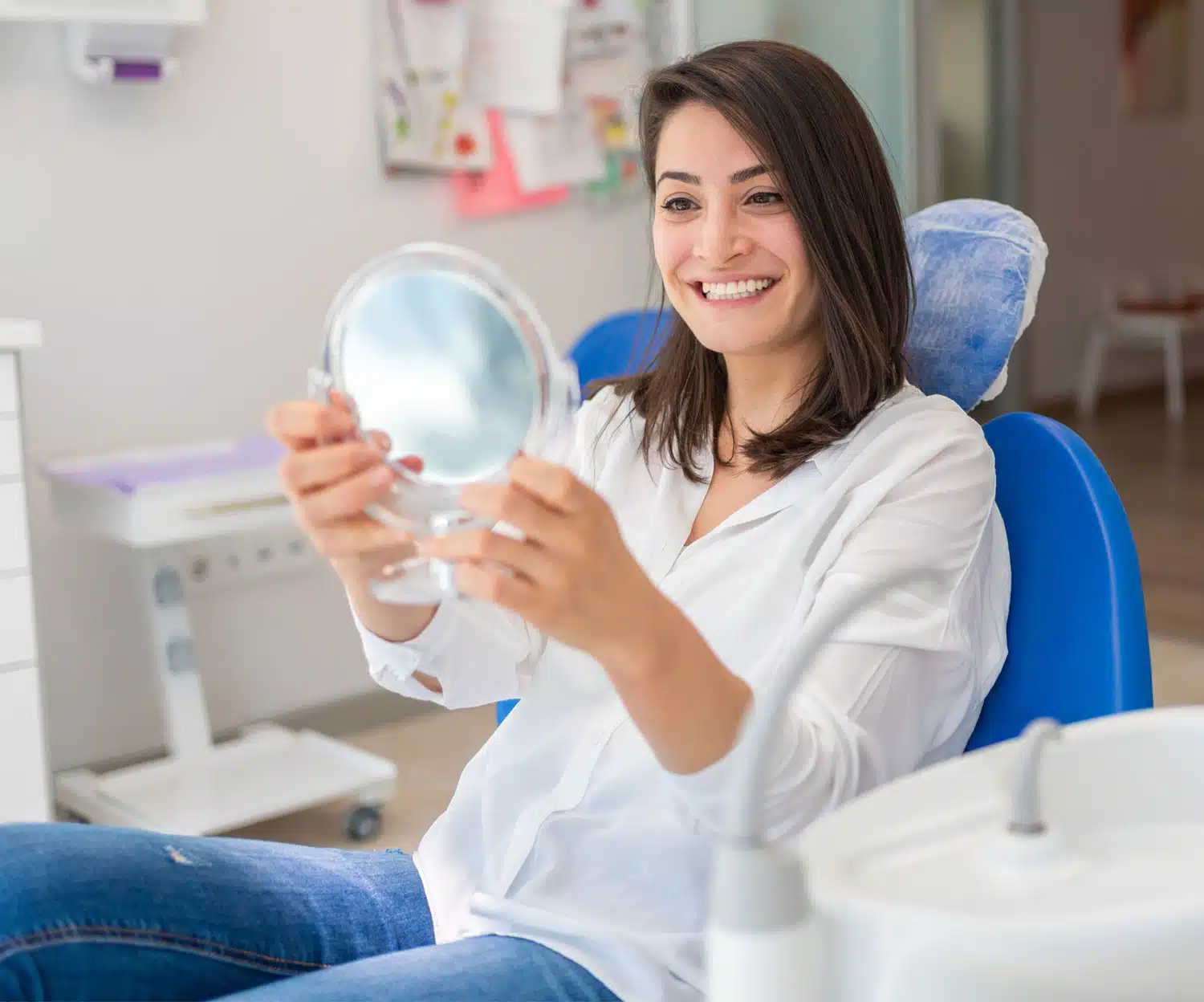 patient sitting in a dentist chair looking happy at the mirror