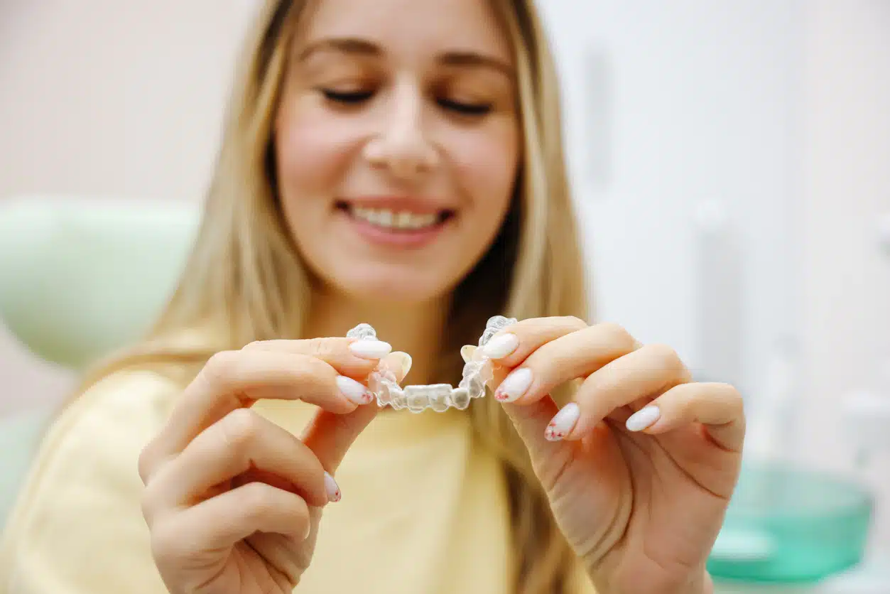 Smiling mid adult woman holding invisible orthodontic retainer